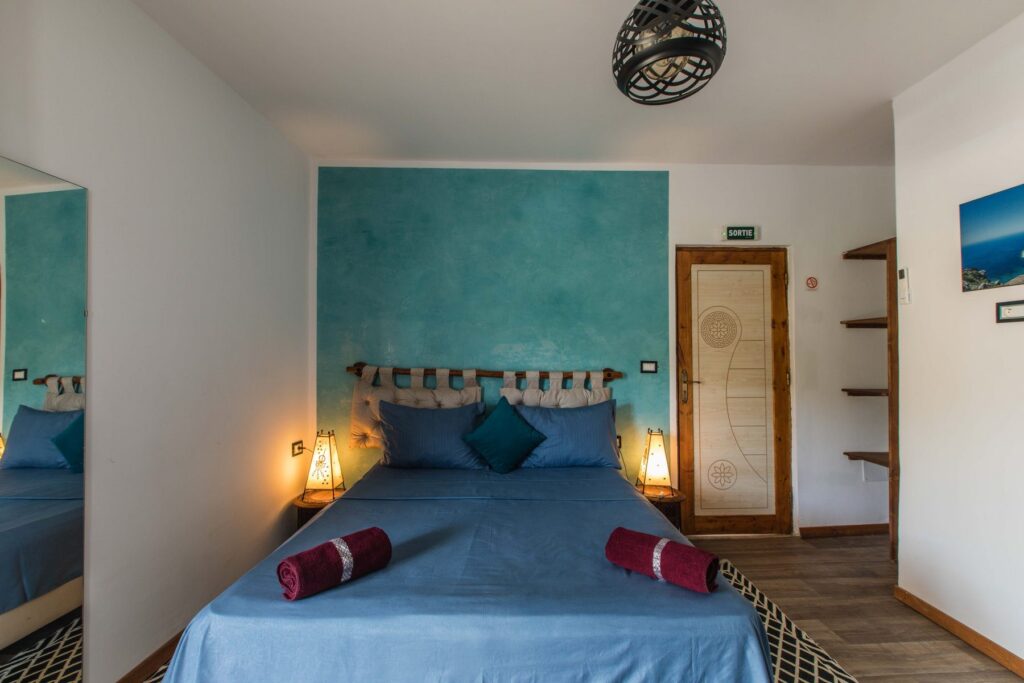 Chambre Fnar – lit double face au mur turquoise, Villa Bella Lina