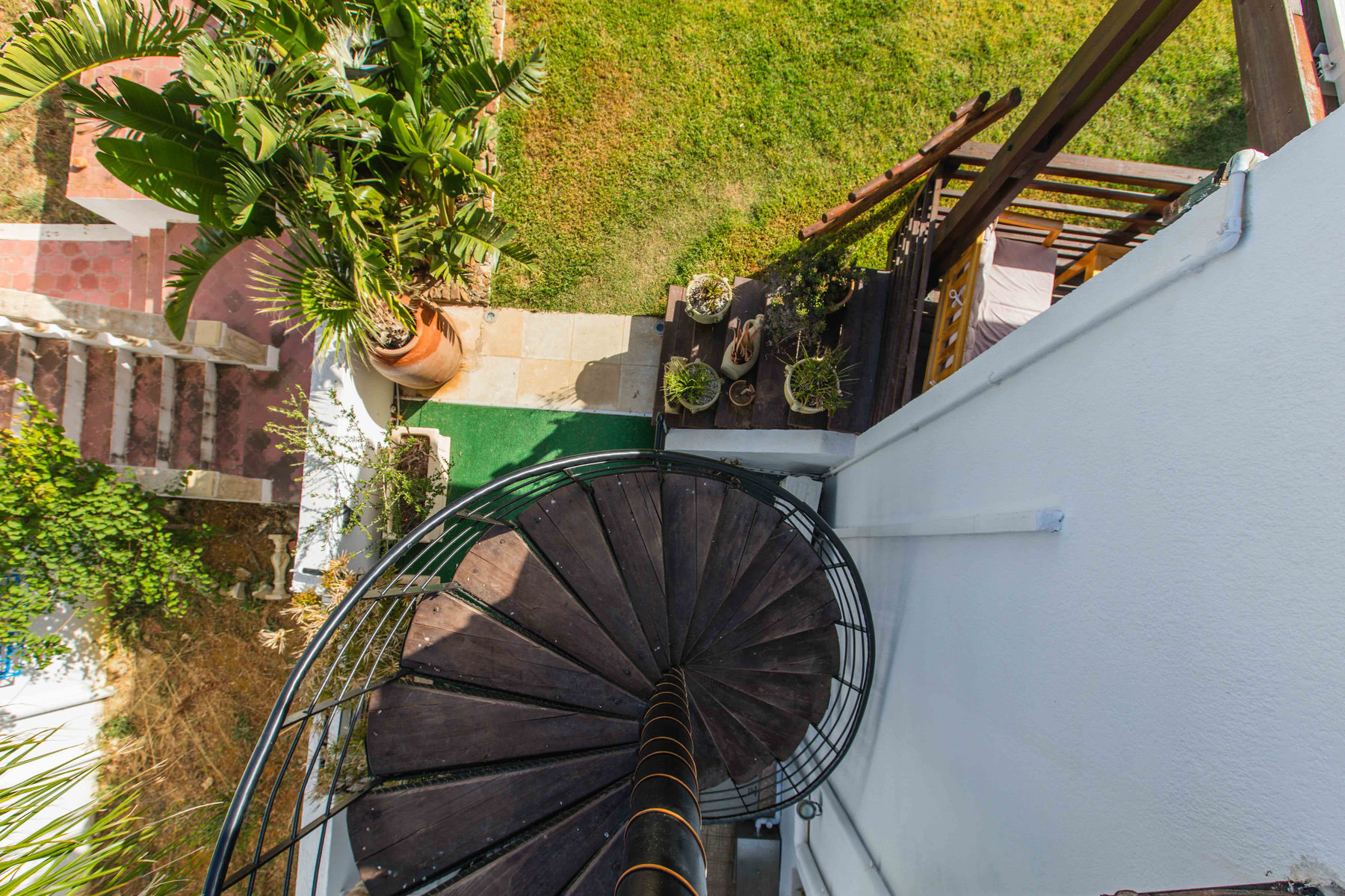Escalier en colimaçon en bois descendant vers le jardin verdoyant de Dar Lina à El Haouaria
